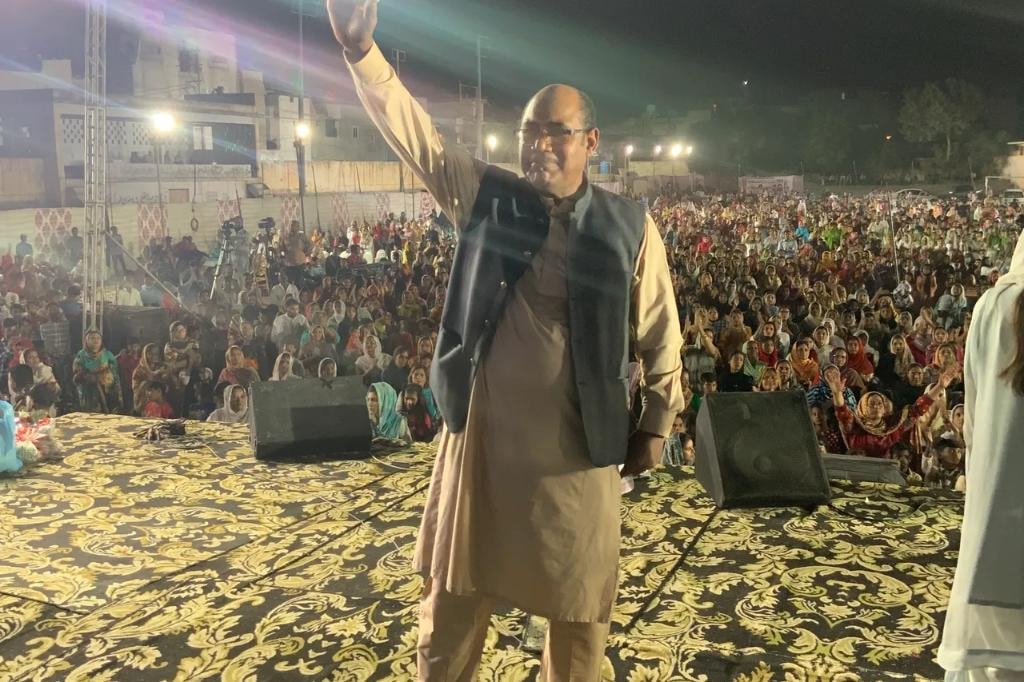 Pastor Larry Birgans on stage with crowd behind him at crusade